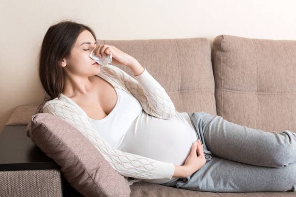 Pregnant woman experiencing stuffy nose symptoms of pregnancy rhinitis